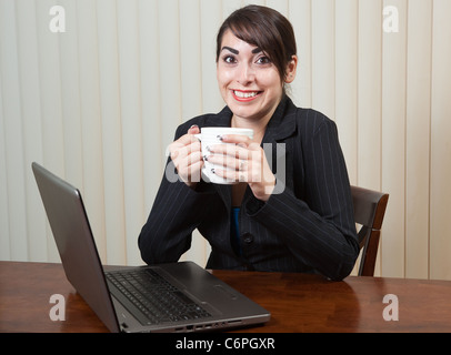 Au-caffienated femme assise à son ordinateur avec une tasse de café Banque D'Images