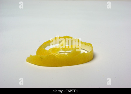 Un zeste de citron se trouve sur un fond blanc Banque D'Images