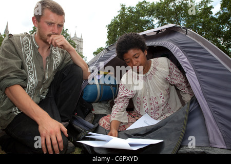 Simon (L) et Anita (R) lire la suite de l'expulsion des articles dans leur tente. La démocratie est aujourd'hui proposé du village date de l'expulsion. Banque D'Images