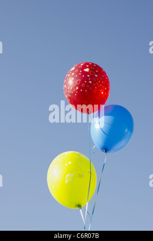 Trois ballons attachés avec des chaînes. Ballons multicolore rouge bleu et jaune avec des cœurs peint. Banque D'Images