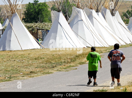 Deux jeunes Américains autochtones marchant le long d'une rangée de tentes sur le Crow réserve au Montana. Banque D'Images