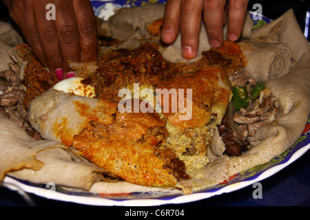 Plaque de base de l'alimentation éthiopienne traditionnelle composé d'injera (une grande crêpe de teff) et du ragoût Banque D'Images