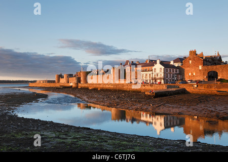 L''Anglesey pub et remparts de la ville éclairée par la lumière du soleil du soir reflète dans les eaux du détroit de Menai encore à marée basse. Caernarfon Gwynedd North Wales UK Banque D'Images