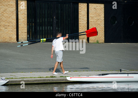 Un homme portant des rames pour un bateau d'aviron, huit sur la rivière Cam à Cambridge. Banque D'Images