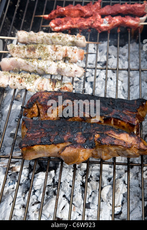 Les brochettes de poulet et côtes levées de porc cuisson sur grill Banque D'Images