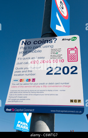 Inscrivez-vous dans une gare parking invitant les visiteurs à payer pour le stationnement avec leur téléphone mobile. Banque D'Images