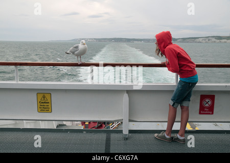 Jeune fille regarde vers le bas un goéland argenté (Mouette) sur un ferry DFDS Seaways entre Douvres en Angleterre et de Dunkerque, France. Banque D'Images