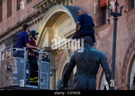 Elle : Bologne, un réfugié marocain a grimpé sur la statue de Neptune dans la Piazza Maggiore, protestant, pour le permis de résidence. Banque D'Images