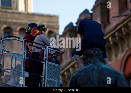 Elle : Bologne, un réfugié marocain a grimpé sur la statue de Neptune dans la Piazza Maggiore, protestant, pour le permis de résidence. Banque D'Images