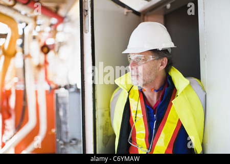 Worker standing in doorway sur plate-forme pétrolière Banque D'Images