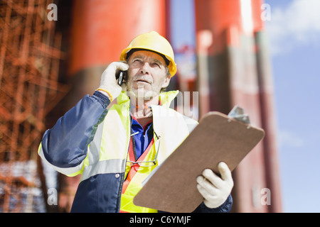 Worker talking on cell phone on oil rig Banque D'Images