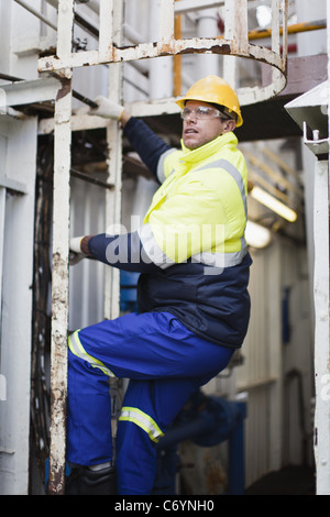 Worker climbing ladder sur plate-forme pétrolière Banque D'Images