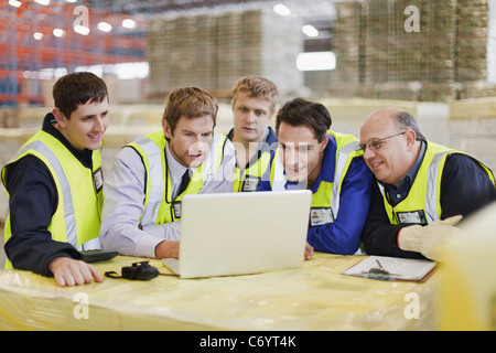 Les travailleurs utilisant un ordinateur portable dans l'entrepôt Banque D'Images