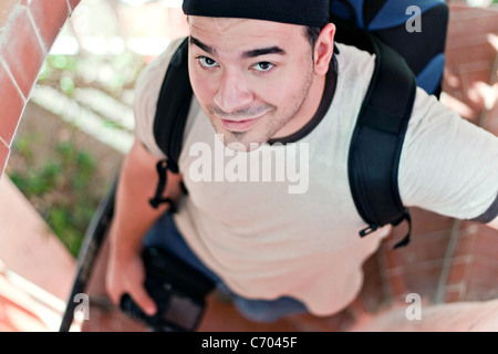 Portrait d'un jeune voyageur avec votre appareil photo reflex numérique à la main et sac à dos. L'italien à la brunette guy dans son 20s. Banque D'Images