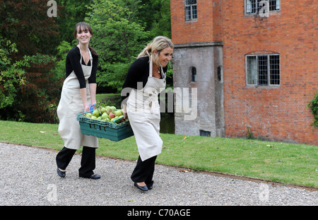 Deux jeunes femmes portant la récolte des pommes England Uk Banque D'Images