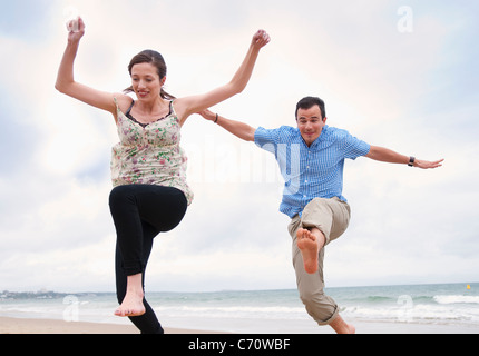 Couple jumping on beach Banque D'Images