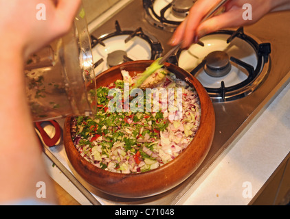 Jeune femme 20s utilisant des ingrédients frais de fabrication de coleslaw dans sa cuisine maison Banque D'Images