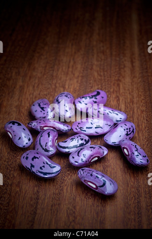 Scarlet runner beans (Phaseolus coccineus), photographié en studio sur une carte de bois exotiques. Fèves de haricot d'Espagne. Banque D'Images