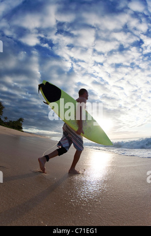 Jeune homme marchant à la surf à Rocky Point, sur la côte nord d'Oahu, Hawaii. Banque D'Images