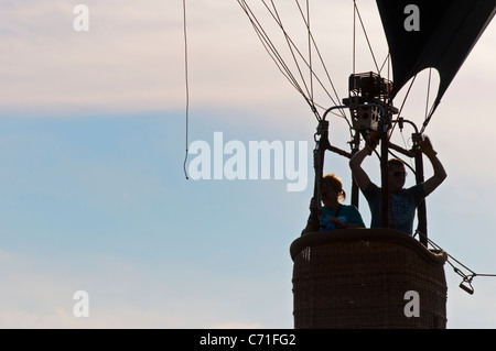 Un ballon à air chaud avec deux personnes passant devant une vague silhouette ciel bleu Banque D'Images