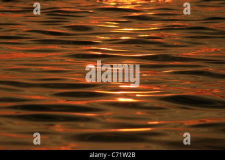 Coucher du soleil orange reflétée sur l'eau avec la texture d'ondulation Banque D'Images
