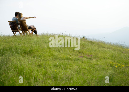 Couple assis sur des chaises sur le dessus de la colline à la vue, à distance en direction de femme Banque D'Images