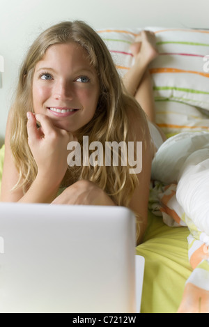 Young woman relaxing in bed with laptop computer Banque D'Images