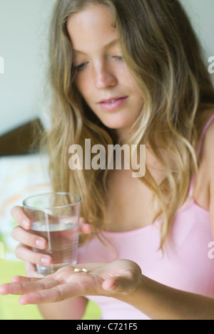 Jeune femme se préparant à prendre des pilules avec un verre d'eau Banque D'Images