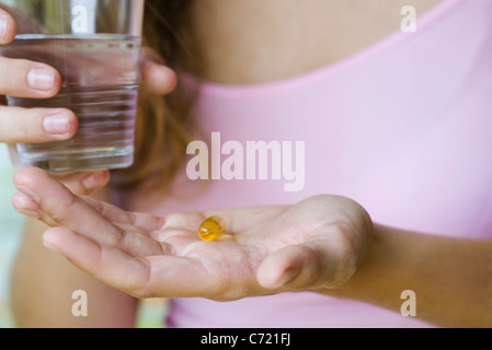 Jeune femme tenant vitamines et verre d'eau, cropped Banque D'Images