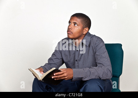 Teenage boy reading Bible jusqu'à la méditation prière reflétant la diversité raciale multi multiculturelles la diversité raciale Pearson Myrleen Banque D'Images