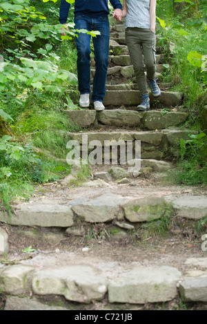 Couple walking down marches de pierre dans les bois Banque D'Images