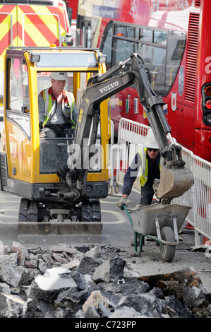 Travailleurs de la visualisation aérienne et minipelle hydraulique travaillant sur route dans la voie de bus à côté de la circulation bourrage de rouge à deux étages Bus Regent Street West End Londres Royaume-Uni Banque D'Images