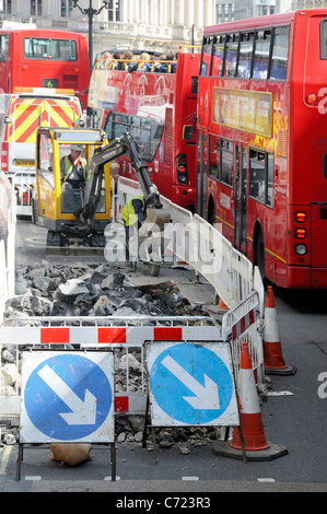 Travailleurs de la visualisation aérienne et minipelle hydraulique travaillant sur route dans la voie de bus à côté de la circulation bourrage de rouge à deux étages Bus Regent Street West End Londres Royaume-Uni Banque D'Images