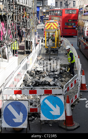 Travailleurs de la visualisation aérienne et minipelle hydraulique travaillant sur route dans la voie de bus à côté de la circulation bourrage de rouge à deux étages Bus Regent Street West End Londres Royaume-Uni Banque D'Images