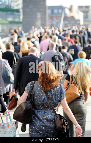 Les gens sur le pont de Londres dos des hommes et femmes des employés de bureau à marcher en direction de la station London Bridge pendant les heures de pointe du soir d'été ensoleillé England UK Banque D'Images