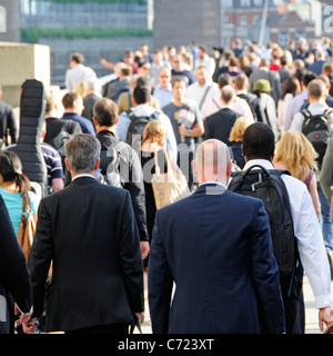 Les gens dos des hommes en costumes et les femmes des employés de bureau sur le pont de Londres à marcher en direction de la station London Bridge banlieusards soir Rush hour England UK Banque D'Images