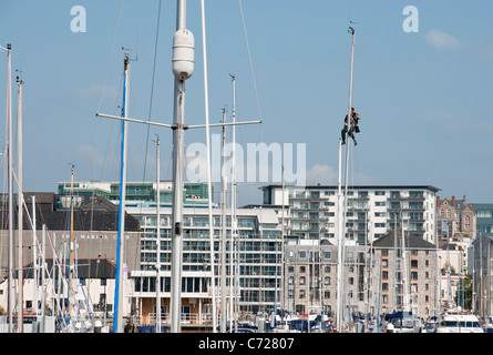 L'homme travaillant en place d'un mât d'un bateau de plaisance amarrés dans le port de Sutton, Plymouth, Devon Banque D'Images