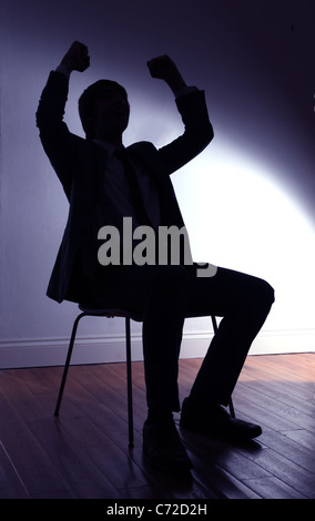 Silhouette d'un jeune homme assis l'air frappe avec ses poings bras levés. Banque D'Images