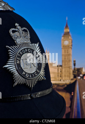 Casque et badge d'agent de police métropolitaine avec chambres du Parlement et rivière Thames Westminster derrière Law Politics Recruitment concept Londres Royaume-Uni Banque D'Images