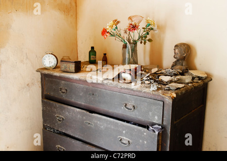Vase de fleurs en plastique, arrêté des horloges et les débris du toit s'est effondré sur les vieux tiroirs bois dans maison à l'abandon. Banque D'Images