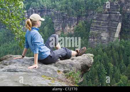 Femme assise sur la falaise donnant sur la plage de distance, Elbsandstein, Saxe, Allemagne, Europe Banque D'Images