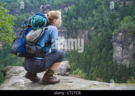 Femme portant un sac à dos s'accroupit au belvédère point dans des montagnes de grès de l'Elbe, Saxe, Allemagne, Europe Banque D'Images