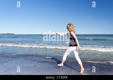 Woman happily courir le long d'une plage Banque D'Images