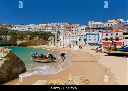 Le Portugal, l'Algarve, Praia do Carvoeiro ville et de la plage avec un bateau de pêche qui reviennent d'un voyage en bateau avec les touristes Banque D'Images