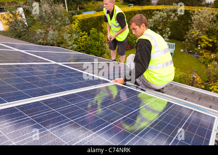 L'installation de panneaux électriques solaires travailleurs sur un toit de maison à Ambleside, Royaume-Uni. Banque D'Images