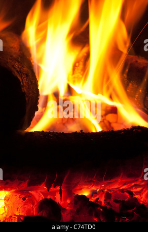 Des bûches brûlent dans une fosse à feu pendant une nuit fraîche ou en camping Banque D'Images