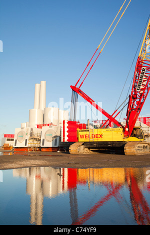 Wind turbine pièces destinées à l'Walneyoffshore wind farm, reflété dans une flaque d'eau sur les quais de Mostyn. Banque D'Images