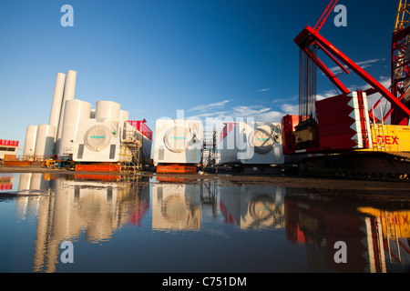 Wind turbine pièces destinées à l'Walneyoffshore wind farm, reflété dans une flaque d'eau sur les quais de Mostyn. Banque D'Images