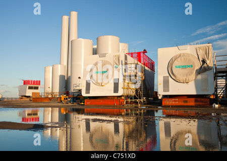 Wind turbine pièces destinées à l'Walneyoffshore wind farm, reflété dans une flaque d'eau sur les quais de Mostyn. Banque D'Images