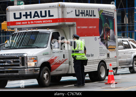 Un agent de police NYPD dirige un camion à travers un poste de contrôle de sécurité sur la 44e Rue, entre la 7e et 8e Avenues. Banque D'Images